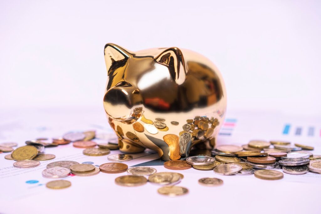 pexels photo 12955822 Shiny golden piggy bank on financial documents with scattered coins symbolizes savings.