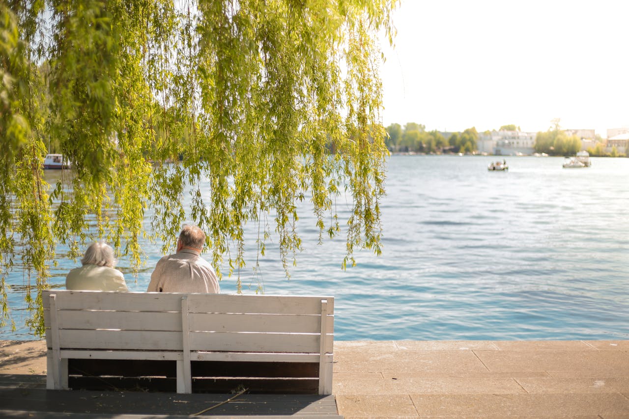 Crafting Captivating Headlines: Your awesome post title goes here Serene scene of an elderly couple sitting on a bench by a lakeside under a willow tree.